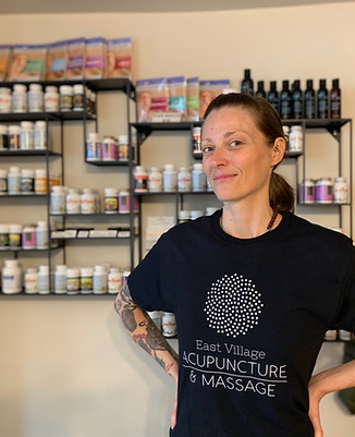 photograph of Kimberly wearing a branded t-shirt standing in front of our herbal pharmacy